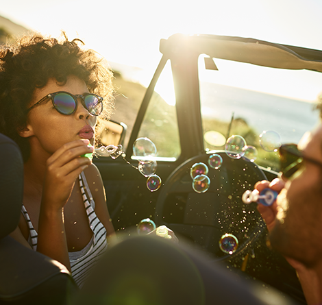 man and women blowing bubbles in convertible